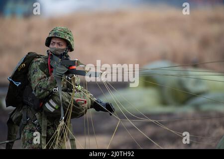 Un paracadutista della forza di autodifesa del suolo giapponese assegnato alla Brigata Airborne 1st raccoglie il suo paracadute dopo l'atterraggio alla zona di goccia al campo combinato di addestramento di armi del centro Fuji, Giappone, 25 gennaio 2022, durante l'esercitazione di Airborne 22. La partnership in corso tra le forze statunitensi e giapponesi continua a dimostrare l'impegno di entrambi i paesi a mantenere la stabilità e la sicurezza in tutta la regione dell'Indo-Pacifico. (STATI UNITI Air Force foto di Senior Airman Brieana E. Bolfing) Foto Stock