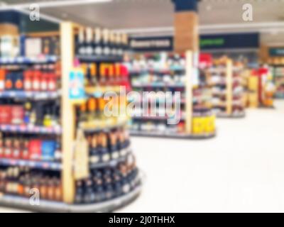 Sfondo offuscato astratto con rack con bottiglie di bevande alcoliche nel negozio Foto Stock