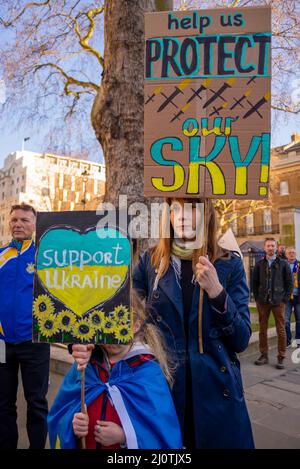 Protesta a sostegno dell'Ucraina in seguito all'invasione del paese da parte della Russia. Cartello che chiede la NATO no fly zone, con madre e figlia Foto Stock