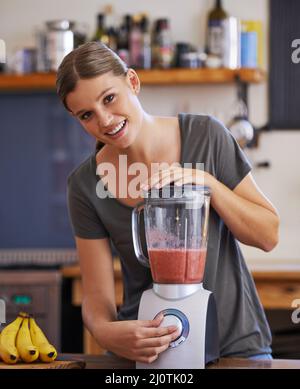 Rendendolo così liscio. Ritratto di una giovane donna attraente che prepara un frullato di frutta. Foto Stock