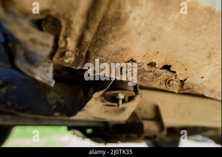 Primo piano interventi di riparazione e saldatura della carrozzeria necessari. Ruggine su una vecchia auto grigia. Foro di ruggine su una vecchia superficie metallica verniciata usurata. Foto Stock