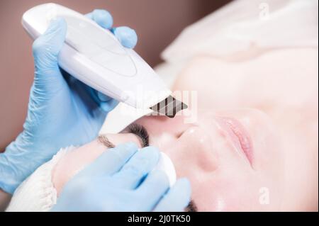 Primo piano pulizia professionale del viso. Procedura meccanica di pulizia del viso a ultrasuoni. Pelatura della pelle del viso. Foto Stock