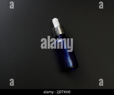 Pipetta in flacone di vetro su sfondo nero. Concetto di farmacia. Pelle di collagene. Mockup Skincare prodotto cosmetico Foto Stock