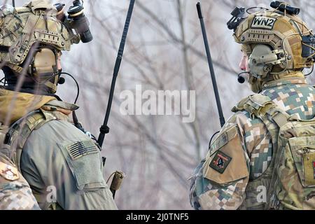 Il personale militare delle forze Armate nazionali lettoni lavora fianco a fianco con i soldati dell'esercito statunitense assegnati a Battery C, Battaglione 1st, reggimento dell'artiglieria da campo 120th, Guardia Nazionale dell'Esercito del Wisconsin, mentre conduce una stretta formazione di supporto aereo durante lo Sciopero settentrionale 22-1 ("Sciopero invernale") presso il National All-Domain Warfighting Center, Grayling, Michigan, gennaio 26, 2022. “Winter Strike”, l’iterazione invernale del programma di esercizi dello sciopero settentrionale, si svolge presso il National All-Domain Warwfighting Center del Michigan settentrionale. Il NADWC è il luogo perfetto per le unità del reparto DEF Foto Stock