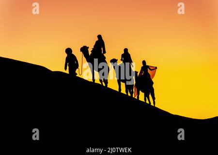 I tre Riders e il loro Handler attraversano il deserto del Sahara sui loro cammelli in Marocco Foto Stock