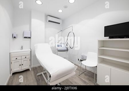 Cabina con tavolo coperto di carta in una clinica di bellezza con apparecchio per trattamenti cutanei e drenanti Foto Stock