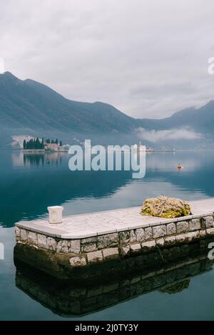 Molo che si affaccia sulle piccole isole nella baia di Cattaro Foto Stock