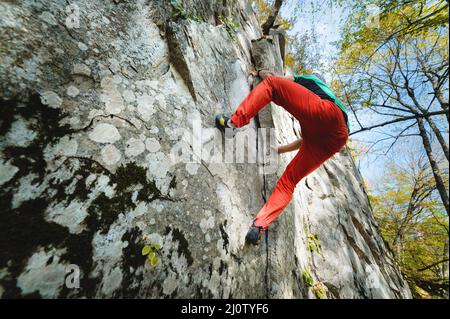 Un uomo bearded invecchiato con un sacchetto di magnesia e scarpe di roccia è addestrato su una roccia non alta nei boschi. Formazione di scalatori in n Foto Stock