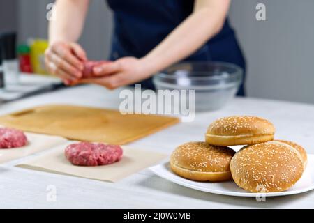 Mano della donna che forma una carne di manzo per una festa di hamburger. Porzionamento carne macinata. Hamburger fatti in casa. Fare il cibo a casa. Foto Stock