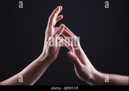 A close-up of two hands male and female gently touch each other. The concept tremulous rejection between the sexes Foto Stock
