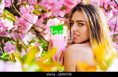 Bella donna con shampoo o balsamo. Ragazza giovane con bottiglia di balsamo. Maschera per capelli. Prodotto di bellezza. Foto Stock