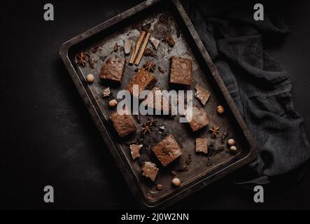 Pezzi di torta brownie al cioccolato al forno in un foglio di metallo da forno su un tavolo nero, vista dall'alto Foto Stock