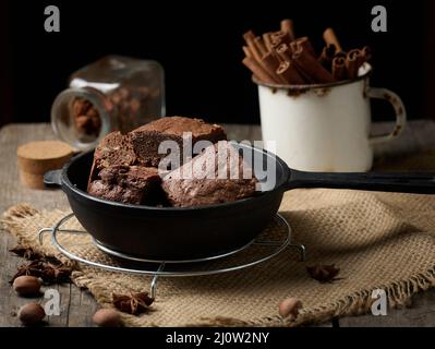 Pezzi di brownie al forno in una padella nera di metallo sul tavolo Foto Stock