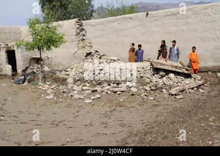 Lal pur, Afghanistan. 20th Mar 2022. La gente si trova a fianco di un muro danneggiato dopo le inondazioni del distretto di Lal pur, nella provincia di Nangarhar, in Afghanistan, il 19 marzo 2022. Le inondazioni improvvise causate da forti piogge hanno causato due vittime e hanno distrutto centinaia di ettari di terreni agricoli nel distretto di Lal pur della provincia orientale di Nangarhar in Afghanistan sabato, il capo distrettuale Qari Abubakr ha detto Domenica. Credit: Amidullah/Xinhua/Alamy Live News Foto Stock