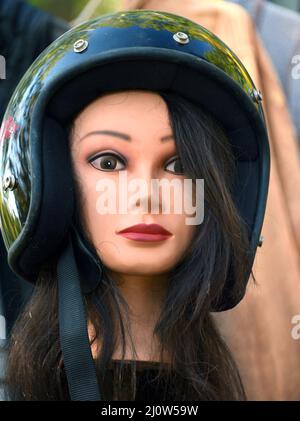 La testa di manichino, che si trova nel mercato delle pulci, ha un intento e uno sguardo fisso. La testa femminile ha capelli lunghi e casco per moto. Foto Stock