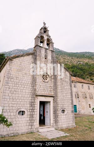 Facciata di un antico campanile in pietra con tre campane sullo sfondo delle montagne Foto Stock