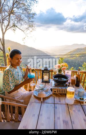 Cena nelle montagne di Chiang mai Thailandia, barbecue da tavolo, uomo asiatico utilizzando cucina pinze grigliare manzo e pancetta sul piatto griglia. Foto Stock