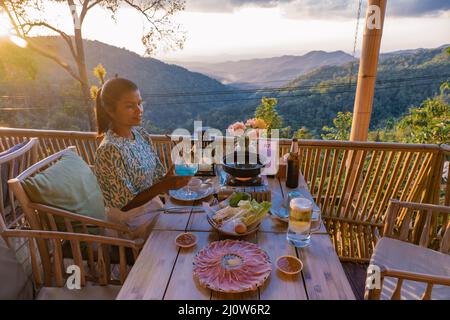 Cena nelle montagne di Chiang mai Thailandia, barbecue da tavolo, uomo asiatico utilizzando cucina pinze grigliare manzo e pancetta sul piatto griglia. Foto Stock