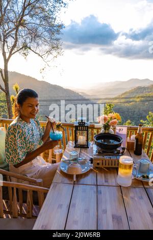 Cena nelle montagne di Chiang mai Thailandia, barbecue da tavolo, uomo asiatico utilizzando cucina pinze grigliare manzo e pancetta sul piatto griglia. Foto Stock