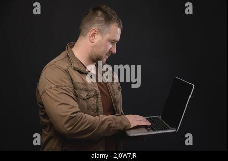 L'uomo caucasico di mezza età usa un computer portatile mentre si trova in studio. Ritratto di un freelance che naviga in Internet Foto Stock
