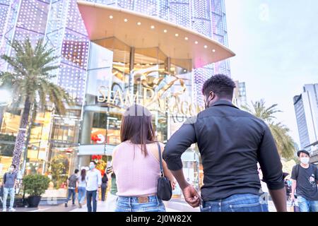 Ritorno di amici multietnici che camminano in un centro commerciale affollato Foto Stock