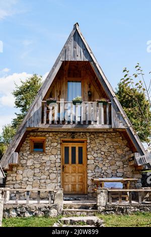 Casa triangolare a due piani con terrazza, tavolo e panca all'ingresso. Montenegro Foto Stock