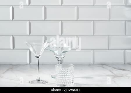 Bicchieri vuoti in vetro per martini, champagne, cocktail alcolici e analcolici come Margarita o Manhattan su tavolo di marmo Foto Stock
