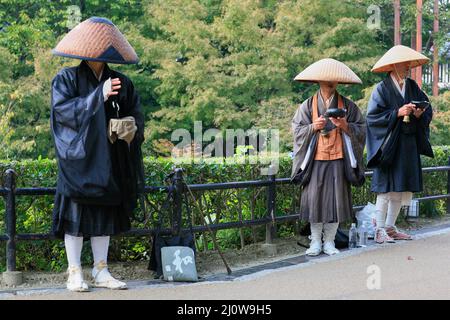 I monaci buddisti praticano il takuhatsu cantando sutra e raccogliendo donazioni in via Kyoto. Giappone Foto Stock