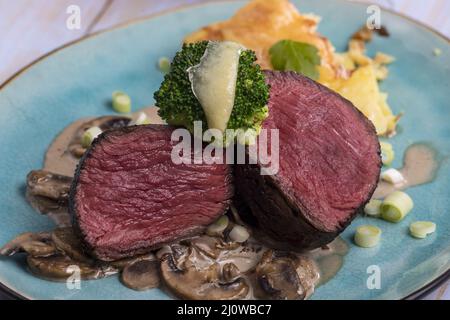 Tagliare la bistecca e il gratin di patate sul piatto Foto Stock