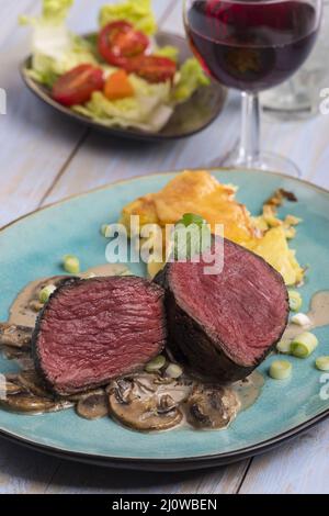 Tagliare la bistecca e il gratin di patate sul piatto Foto Stock