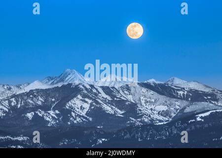 luna piena che sorge sulle montagne pazze vicino a wilsall, montana Foto Stock