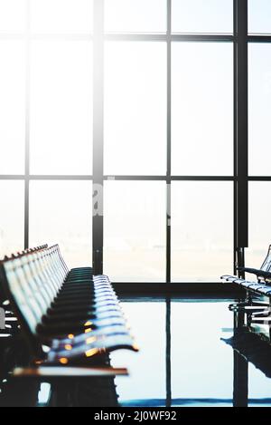 Le avventure iniziano nell'area d'attesa. Shot di file di posti a sedere in una sala di partenza aeroporto vuota. Foto Stock