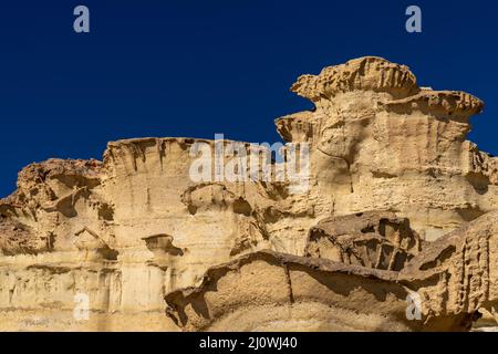 Una vista delle famose erosioni di arenaria e degli hoodoos a Bolnuevo sotto un cielo blu chiaro Foto Stock