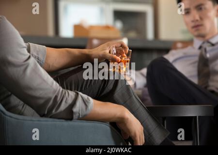 Primo piano di giovani uomini d'affari cinesi che tengono un bicchiere di whisky Foto Stock