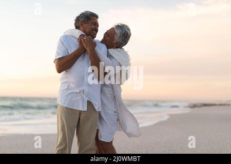 Allegro giovane coppia multirazziale senior che si guarda l'un l'altro mentre abbraccia durante il tramonto Foto Stock