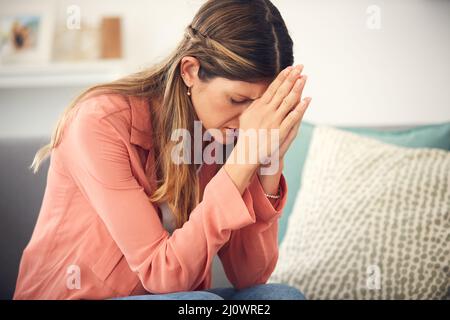 Spero che la cosa vada meglio. Scatto corto di una giovane donna che guarda turbata mentre si siede a casa. Foto Stock