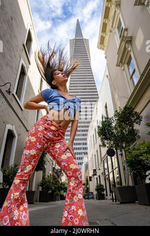 Adolescente donna che indossa abiti in stile 60s con l'iconica San Francisco Skyline in background Foto Stock