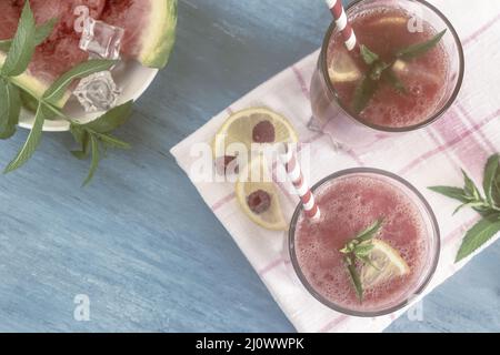 Succo di anguria in un bicchiere con limone e lamponi. Foto Stock