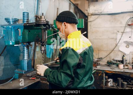 Il lavoratore che lavora con la trivella lavora in una fabbrica di metallo Foto Stock