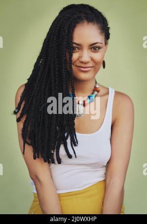 Drappeggiato in splendidi dreads. Ritratto di una giovane donna attraente in posa su sfondo verde. Foto Stock