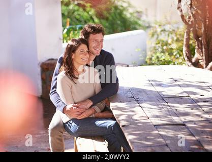 Condividere un momento di gara. Una coppia seduta ad un tavolo di legno sotto le foglie d'autunno. Foto Stock