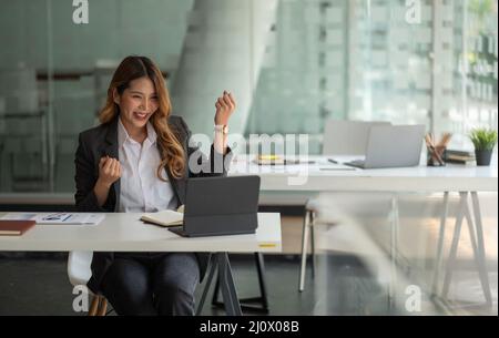 Ritratto attraente giovane donna asiatica d'affari con tablet digitale celebrare il successo o felice posa. Foto Stock