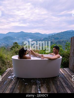 Vasca da bagno durante il tramonto sulle montagne di Chiang mai Thailandia, sete nella vasca idromassaggio all'aperto con fuoco di legno nella natura selvaggia Foto Stock