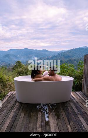 Vasca da bagno durante il tramonto sulle montagne di Chiang mai Thailandia, sete nella vasca idromassaggio all'aperto con fuoco di legno nella natura selvaggia Foto Stock