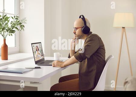 Uomo attento che guarda la formazione aziendale, il webinar online o parla con una videochiamata. Foto Stock