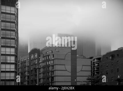 Nebbia in città. Immagine in bianco e nero di alti edifici ricoperti di fitta nebbia in una giornata di pioggia nuvolosa. Foto Stock