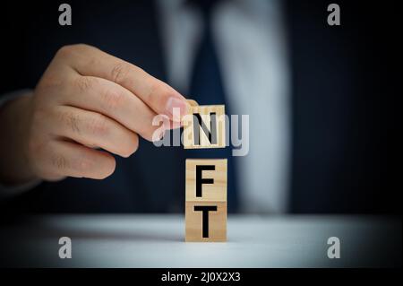 L'uomo mette insieme la parola NFT da blocchi. Token non-fungibile NFT. Tecnologia astratta. Concetto NFT Foto Stock