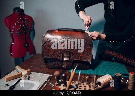 Tanner donna che fa articoli in pelle in officina. Processo di lavorazione del cuoio artigiano Foto Stock