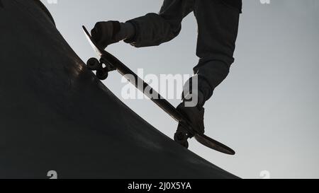 Adolescente che si diverte con la silhouette del parco skateboard. Concetto di foto di alta qualità Foto Stock