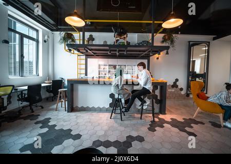 Gruppo di uomini d'affari multietnici occasionali che prendono pausa dal lavoro facendo cose diverse mentre godendo di tempo libero in relax Foto Stock